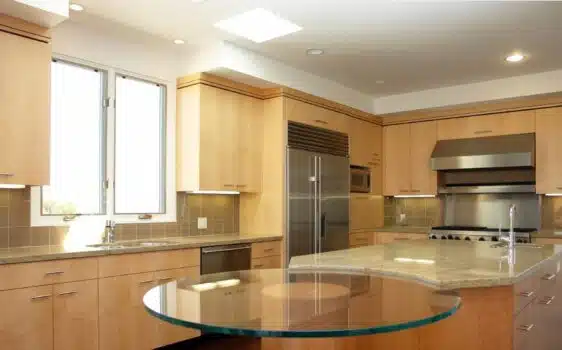 Glass dinner table connected to a kitchen island.