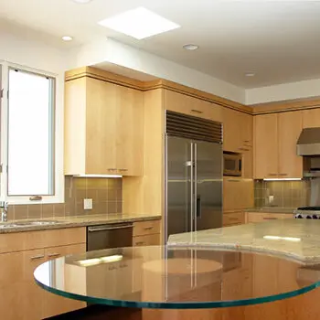 Glass dinner table connected to a kitchen island.